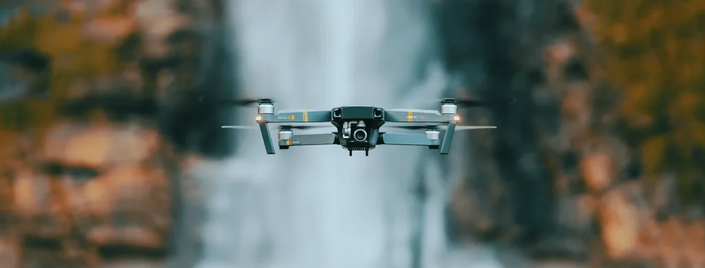 DJI Mavic Pro hovering in front of a waterfall surrounded by autumn foliage