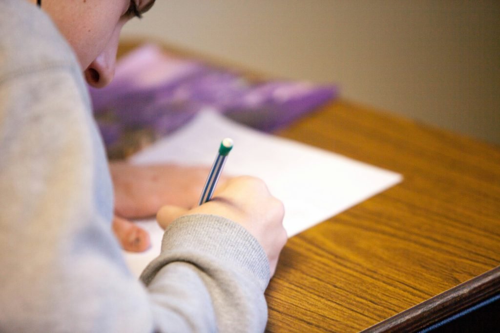 Student writing answers on paper at a desk while preparing for a Transport Canada exam